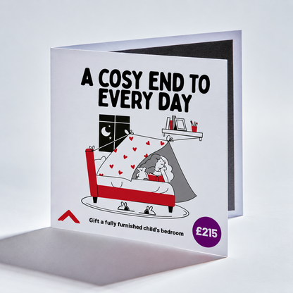 A square greeting card shown standing open against a light gray studio background. The front has a white base with black text reading 'A COSY END TO EVERY DAY,' a cartoon bedroom scene with a red bed, gray tent, black nightstand, and small red hearts, plus a purple price bubble reading '£215.