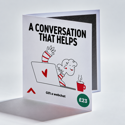 A folded greeting card standing open on a light gray studio background. The front of the card is white with bold black text reading 'A CONVERSATION THAT HELPS,' a cartoon character sitting in a laptop with a red heart on the screen, a red mug, and a green circle that says '£23.