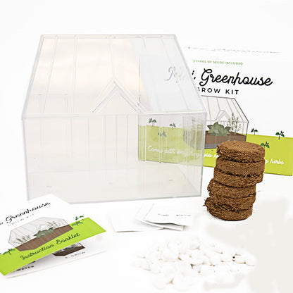 The elements of the green house grow kit; including a mini greenhouse structure, a stack of soil and a manual.
