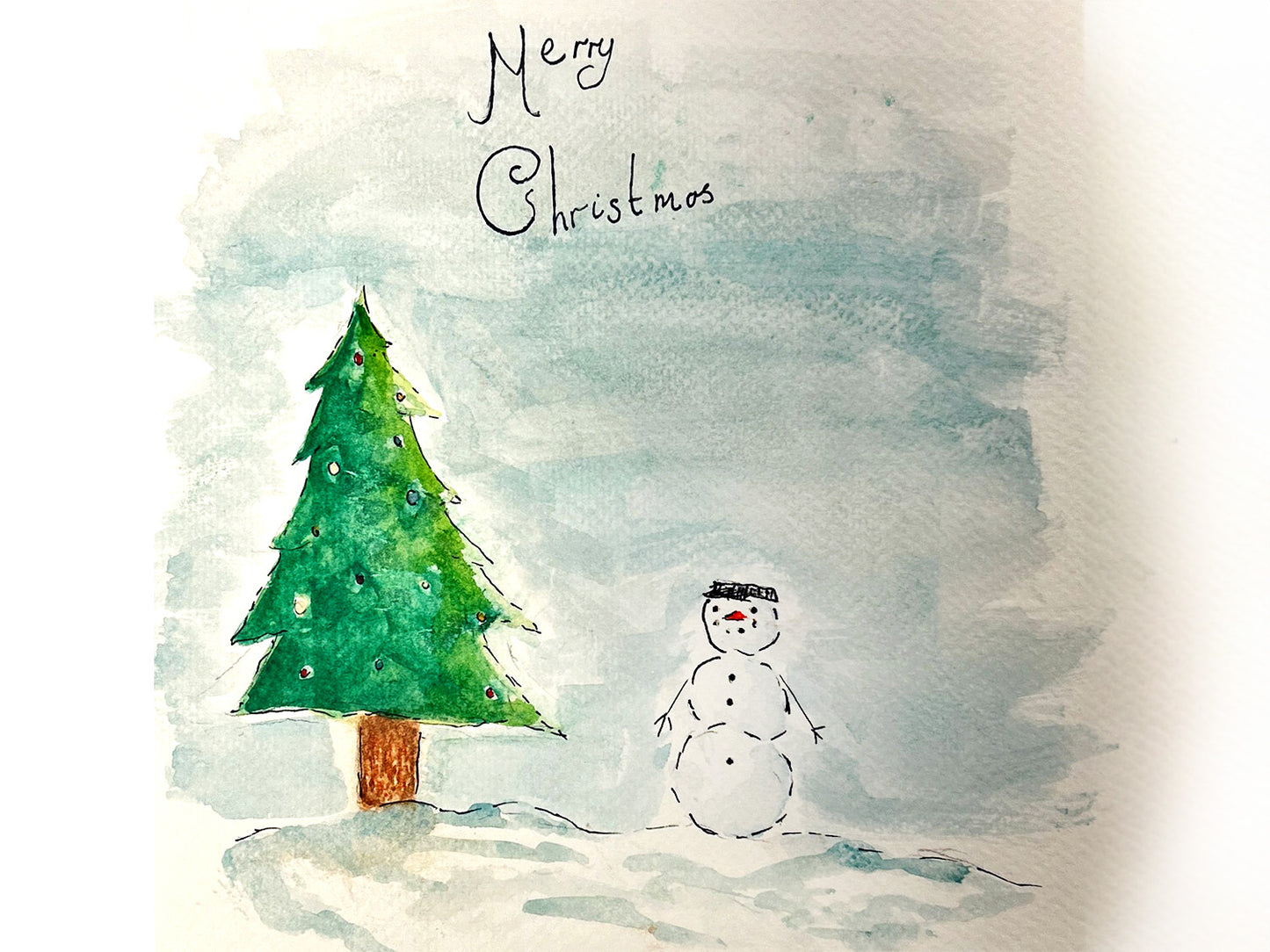 A watercolour painting of a Christmas snowman against a snowy background. The copy reads 'Merry Christmas'