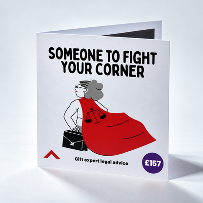 A folded white greeting card standing upright on a light gray studio background. The card features the bold black text 'SOMEONE TO FIGHT YOUR CORNER' above an illustration of a woman in a red dress holding a briefcase and scales of justice, with a purple circle reading '£157' and small text 'Gift expert legal advice' near the bottom.