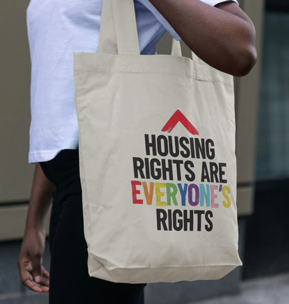 Natural canvas colour tote bag with slogan "Housing rights are everyone's rights" The word everyone's is in the LGBTQ+ flag colours