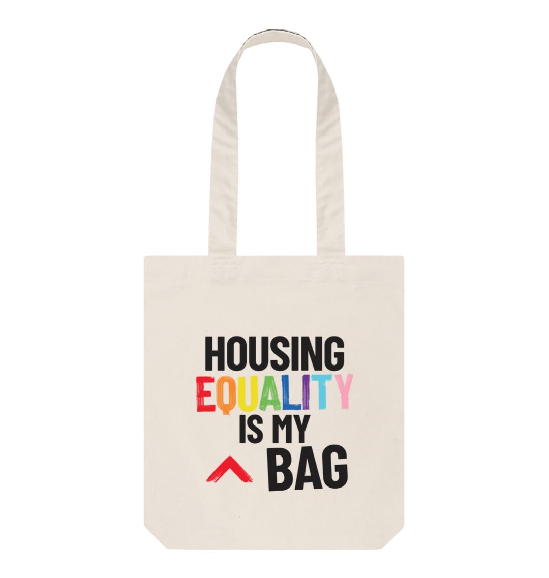 natural canvas colour tote bag with bold slogan "housing equality is my bag" the word equality is in the LGBTQ+ flag colours and the rest of text in black bold lettering