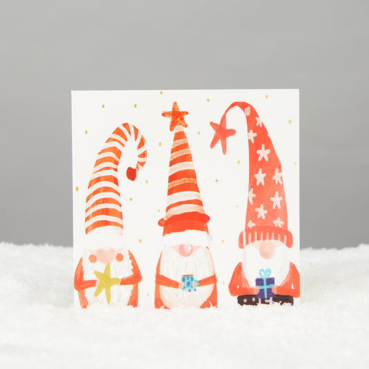three gonks in big hats holding gifts like wise men. square card