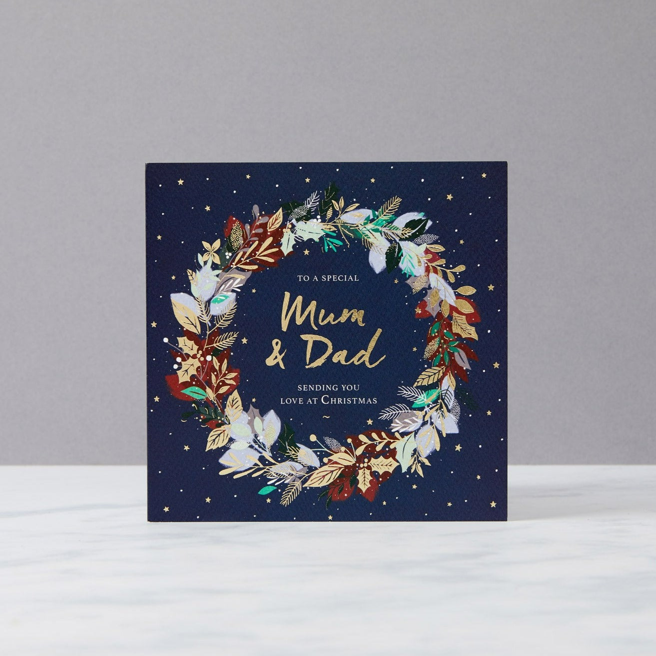 navy card with gold stars and wreath reads "to a special mum & dad sending you love at Christmas" 